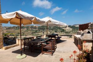 un patio con mesa, sillas y sombrilla en Villeleynah Holiday Home, en Munxar