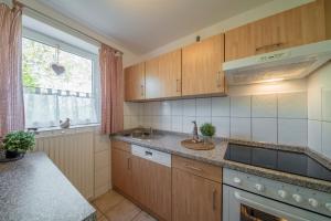 cocina con armarios de madera, fregadero y ventana en Backhaus Ost, en Bisdorf