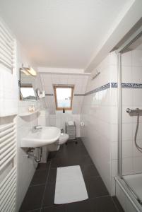 uma casa de banho branca com um lavatório e um chuveiro em Haus Gud Hööb Whg 06 em Wyk auf Föhr