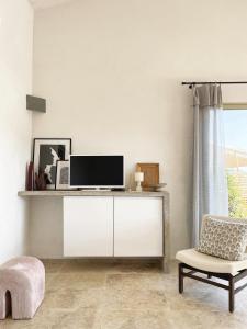 sala de estar blanca con TV y silla en A Casa di Santa Giulia, en Porto Vecchio