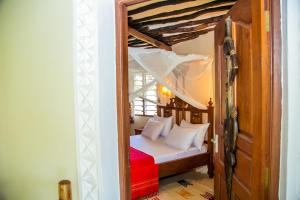 a small bedroom with a bed with a red blanket at 3 Bed Cottage Sleeps 6- Pool Chef Option Parking in Diani Beach