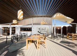 a restaurant with wooden tables and chairs on a deck at Hard Rock Hotel Ibiza in Playa d'en Bossa