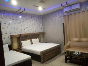 a bedroom with two beds and a chair in it at Hotel Sereena residence in Multan