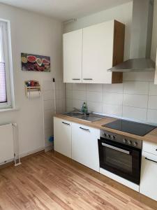 cocina con armarios blancos y fogones negros en familienfreundliche Ferienwohnung Tina en Rollshausen