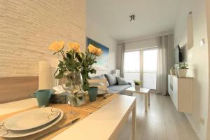 a living room with a table with a vase of flowers at Homely Apartment in Gdańsk