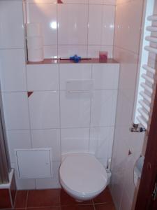 La salle de bains est pourvue de toilettes blanches et d'un mur en carrelage blanc. dans l'établissement Jenatschek, FP, N-1-2, à Heiligenhafen