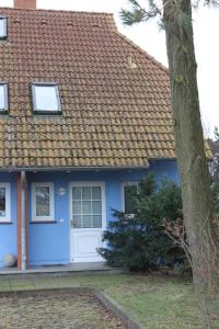 オストゼーバート・ディアーハーゲンにある"Achtern Diek" Doppelhaushälfteの白い扉と木のある青い家