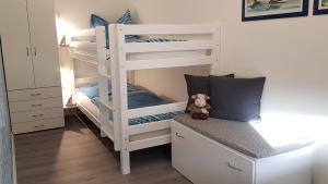 a white bunk bed with a teddy bear in a bedroom at FeWo Aust in Sankt Peter-Ording