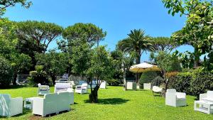 a group of white chairs and an umbrella on the grass at Hotel Alpha in Sant'Agnello