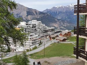 a large white apartment building with mountains in the background at studio 4 pers Puy-Saint-Vincent 1700 in Puy-Saint-Vincent