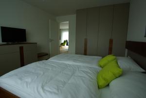 a bedroom with a white bed with green pillows at Friedrichshafen in Bettnau