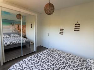 een slaapkamer met een bed en een muur met een spiegel bij Résidence Estey T2 centre avec aperçu Bassin in Andernos-les-Bains