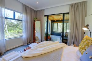 a bedroom with a large bed and large windows at Boshuis Farm Stay in George