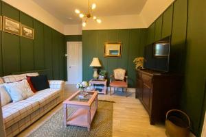 sala de estar con paredes verdes, sofá y mesa en Old City Gem Flat en Aberdeen