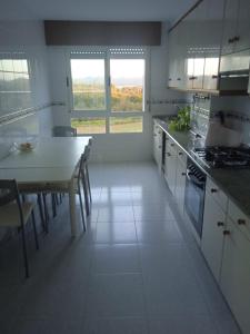 アルスーアにあるLa Casa de Vicentaの白いキャビネットとテーブル付きのキッチンが備わります。