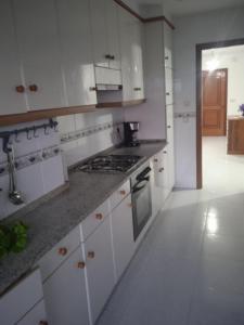 アルスーアにあるLa Casa de Vicentaの白いキャビネットとコンロ付きオーブンを備えたキッチン