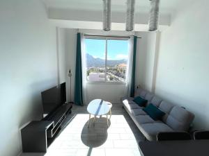 a living room with a couch and a table and a window at Calvi T2 climatisé, wifi, centre-ville, à proximité plage, commerces, taxi & gare, vue plage & montagne in Calvi