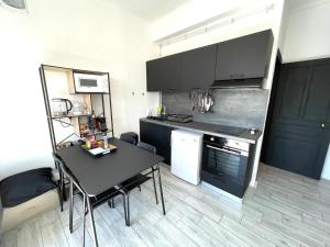 a small kitchen with a black table and a dining room at Calvi T2 climatisé, wifi, centre-ville, à proximité plage, commerces, taxi & gare, vue plage & montagne in Calvi