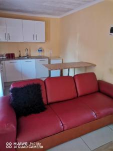 a red couch in a living room with a kitchen at Siyaya’s Guest Palace in Jozini