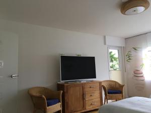 a bedroom with a television on a dresser with two chairs at Stadtferienwohnung in Müllheim