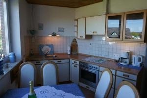 eine Küche mit weißen Geräten und einem Tisch mit einer Flasche Wein in der Unterkunft Carpe Diem II 1322 in Fehmarn