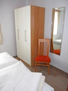 a bedroom with a bed and a mirror and a chair at "Landhaus Voss" Typ 1 Nr2 in Staberdorf