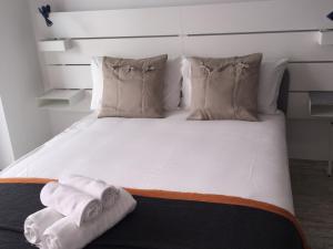 Una cama blanca con almohadas y toallas. en Tomarhousing - Old Town, en Tomar