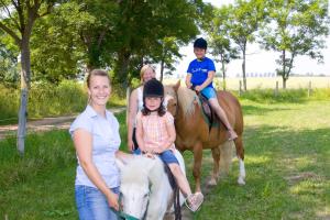 a family is posing for a picture on a horse at "Ferienhof Sporleder" - Landhaus Nr1 in Meeschendorf
