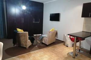 a living room with two chairs and a table at BEAUTIFUL APARTM B10 SITUATED IN BAINS GAME LODGE in Bloemfontein