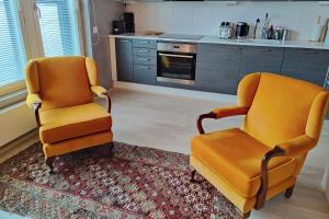 zwei orangefarbene Stühle auf einem Teppich in der Küche in der Unterkunft The Cutest Studio in Central Tampere in Tampere