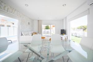 uma sala de estar com uma mesa de vidro e cadeiras brancas em Casa Lusitana da Praia & Casa Lusitana Mare Alta em Porto Covo