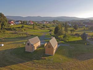 dos pequeños edificios en un campo con montañas en el fondo en Widok na Śnieżkę - domki całoroczne, en Łomnica