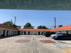 un edificio con coches estacionados en un estacionamiento en The Fly Inn Motel, en Lynwood