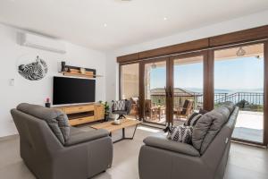Una sala de estar con dos sillas y un televisor de pantalla plana. en Villa Teza, amazing view, en Glavani