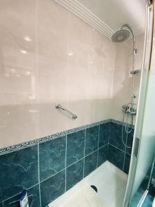 ein Badezimmer mit einer Dusche und einer blau gefliesten Badewanne in der Unterkunft Apartamento Alonso 1 in Getxo