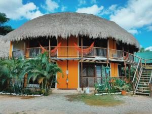 an orange house with a thatched roof at Hostal El Bohío in Palomino