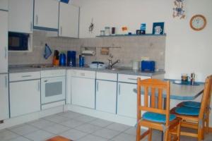 una cocina con armarios blancos, 2 sillas y fregadero en Ferienwohnung Biernat, en Prinzenmoor