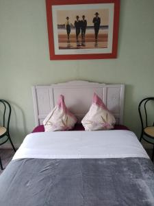 1 dormitorio con cama blanca y almohadas rosas en appartement de letty en Fort-Mahon-Plage