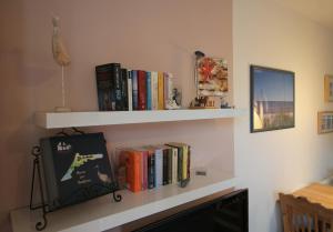 a shelf with books and a picture on a wall at Haus am Bodden in Zingst