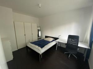 Friedrichshain Apartment في برلين: غرفة نوم بسرير ومكتب وكرسي