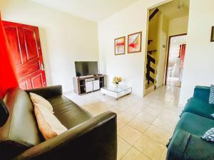 uma sala de estar com um sofá e uma televisão em Casa a 300 metros da praia do Centro - WIFI 200MB - TV Smart - 2 Quartos - Cozinha equipada - Churrasqueira - Pet friendly - Quintal em Rio das Ostras