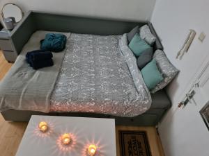 Cama pequeña en habitación con 2 velas en el suelo en Cosy 1 & 2 parking et wifi gratuits en Charleroi