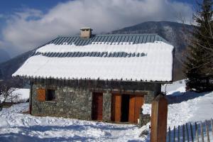 un petit bâtiment en pierre avec de la neige sur le toit dans l'établissement Rustic & A Chalet 'Le Sert du Grey - Vaujany, à Vaujany