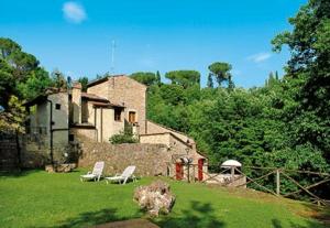 a house with two lawn chairs and a building at Podere il Vecchio Mulino in San Gimignano