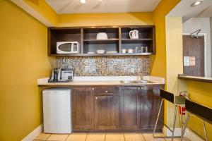 a kitchen with wooden cabinets and a microwave at Town Inn Suites in Toronto