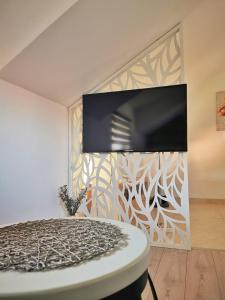 a bedroom with a tv on a wall and a table at Apartman Ananas Banja Luka centar bolnica besplatan parking in Banja Luka