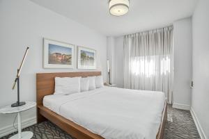 a white bedroom with a large bed and a window at Town Inn Suites in Toronto