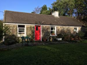 une petite maison en briques avec une porte rouge dans l'établissement Cottage by the Sea, West Cork, Ireland, à Kilbrittain