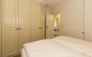 een witte slaapkamer met een bed en een kast bij Quisisana10 in Sankt Peter-Ording