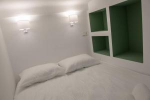 a white bedroom with a bed with two lights and a mirror at The Little big apartment in the heart of Heraklion in Heraklio